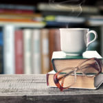 Pile of books, glasses and cup on a table